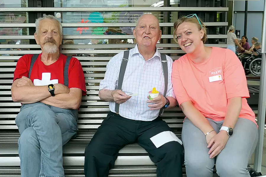 Die beiden Bewohner Leo Strüby (l.) und Hans Amgwerd strahlen mit Katharina Helml, aktivierungsfachfrau HF, um die Wette.